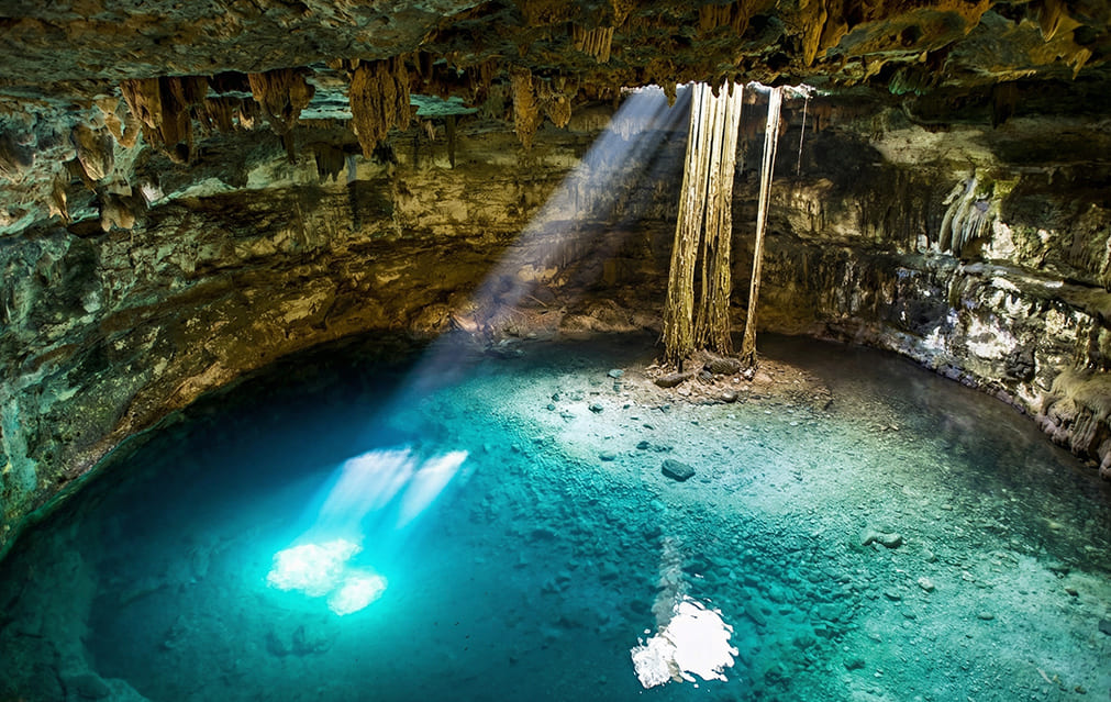 Detalle del haz de luz y raíces en el Cenote Samulá
