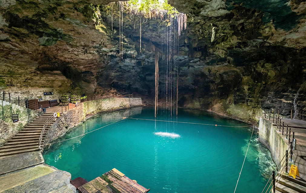 Interior del Cenote Hubiku con rayo de sol iluminando las aguas
